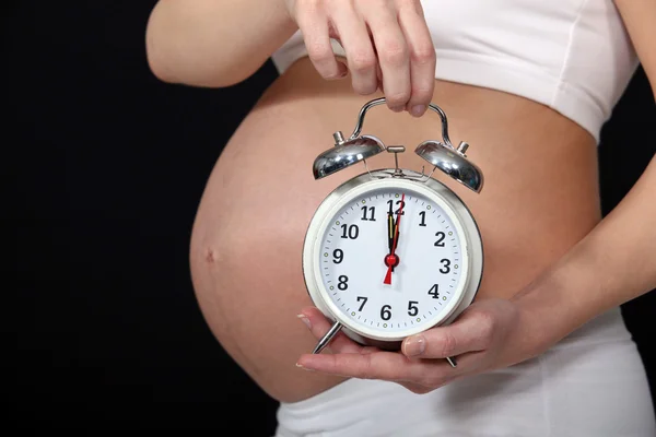 Mulher grávida segurando despertador — Fotografia de Stock
