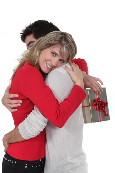 Woman holding gift hugging boyfriend — Stock Photo, Image