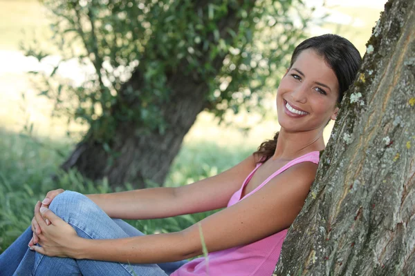 Mujer sentada apoyada contra tronco de árbol —  Fotos de Stock