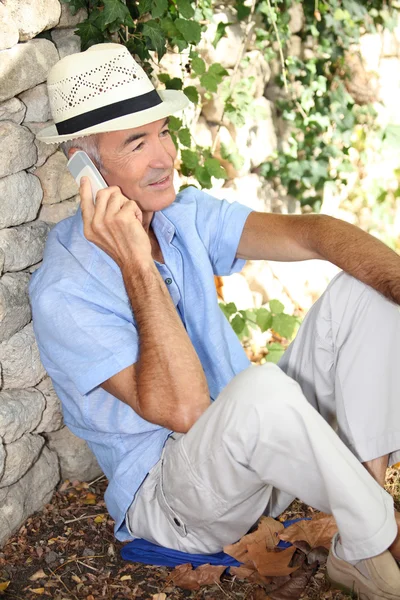 Old man sat by stone wall whilst on vacation — Stock Photo, Image