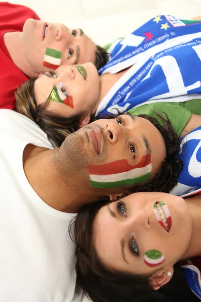Четыре итальянских футбольных фаната лежат на полу — стоковое фото