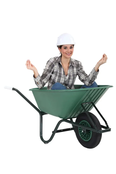 A female construction worker doing yoga in a wheelbarrow. — Stock Photo, Image