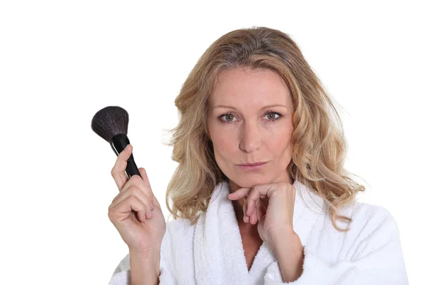 Mujer rubia en albornoz sosteniendo cepillo de maquillaje — Foto de Stock