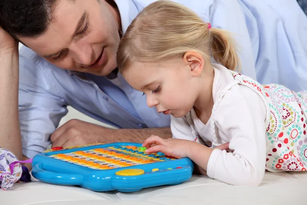 Мужчина играет в игрушечный компьютер с маленькой девочкой — стоковое фото