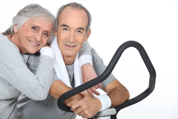 Sportig äldre par med cross trainer — Stockfoto