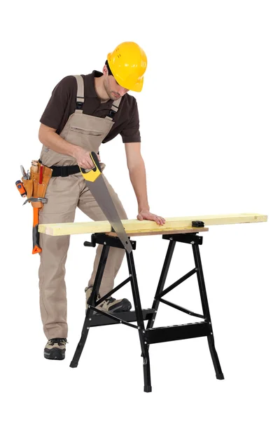 Joiner sawing a plank, studio shot — Stock Photo, Image
