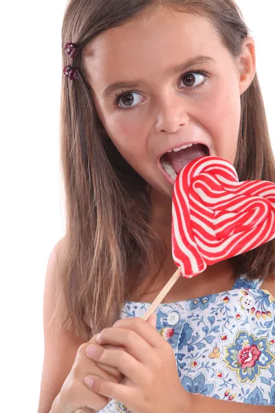 Girl about to lick a heart lollipop — Stock Photo, Image