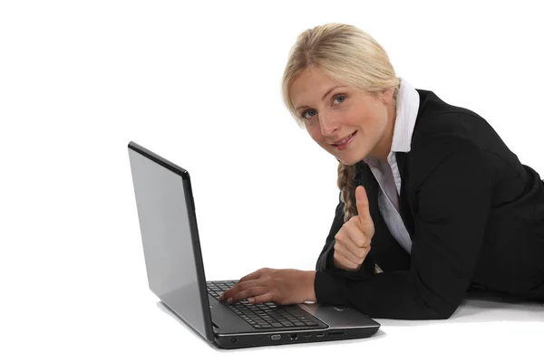 Eine Geschäftsfrau mit ihrem Laptop auf dem Boden liegend. — Stockfoto