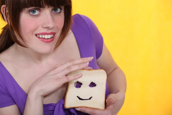 Mulher fazendo um rosto em uma fatia de pão — Fotografia de Stock