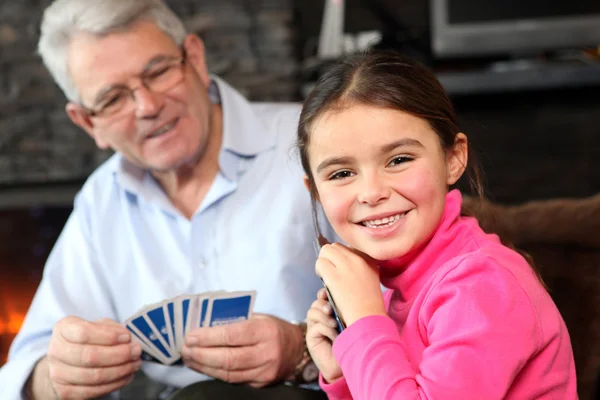Молодая девушка играет в карты с дедушкой — стоковое фото
