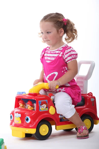 Liten flicka satt på leksaksbil — Stockfoto