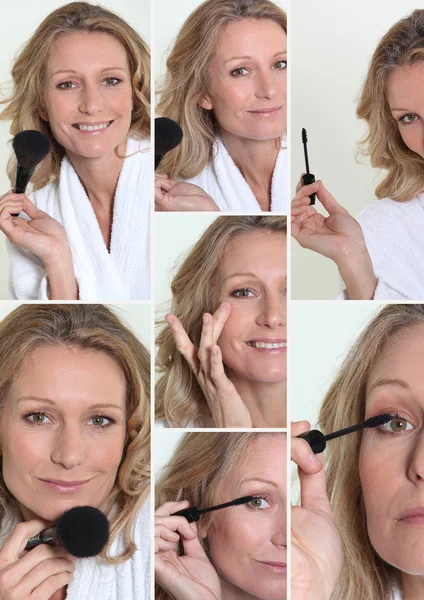 Vrouw in badjas make-up op te zetten — Stockfoto