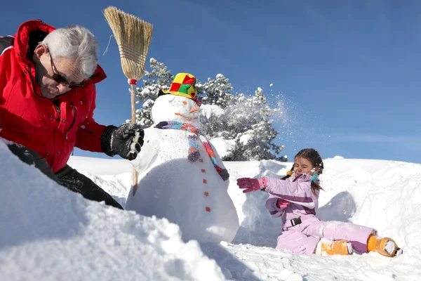 Kleines Mädchen und Großvater basteln einen Schneemann — Stockfoto