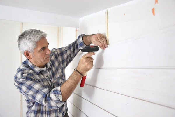 Grey-haired man replacing house paneling — Stock Photo, Image