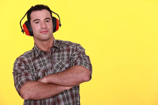 Handyman wearing red protective ear muffs — Stock Photo, Image