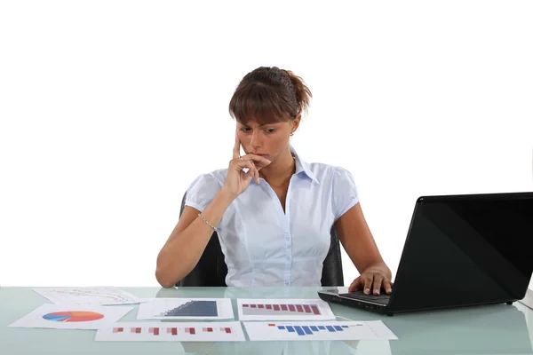Kvinna satt vid skrivbordet omgiven av grafer — Stockfoto