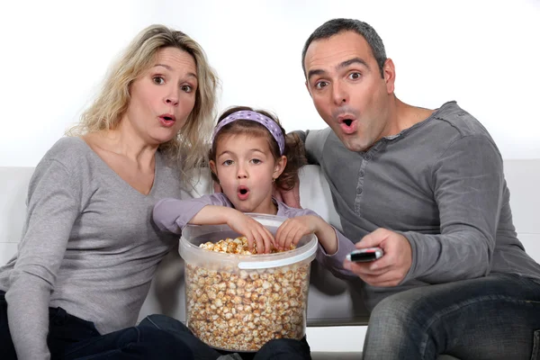 Ailesi ve kızı televizyon izleyip patlamış mısır yiyorlar. — Stok fotoğraf