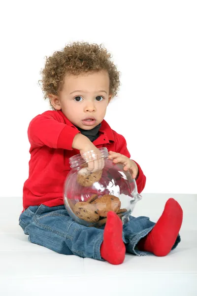 Ребенок берет печенье из банки — стоковое фото