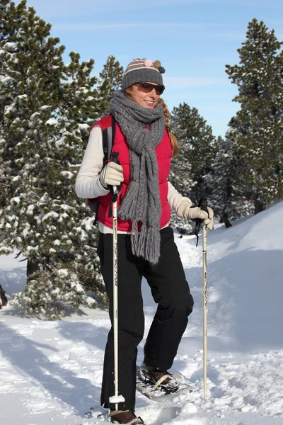 Žena chůze ve sněhu s sněžnice — Stock fotografie