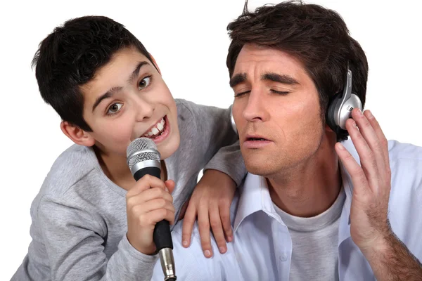 ヘッドフォンとマイクで歌う少年を持つ男 — ストック写真