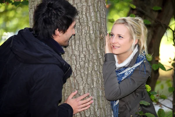Пара ховається по обидві сторони дерева — стокове фото