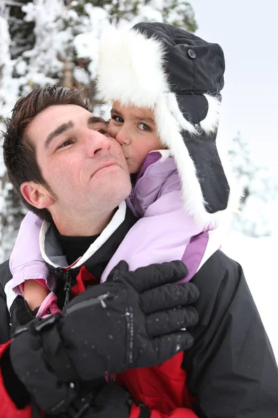 Vater gibt Tochter Huckepack im Schnee — Stockfoto