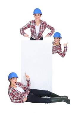 Tradeswomen surrounding a blank sign clipart