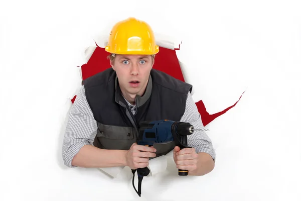 A man popping through the wall with a drill. — Stock Photo, Image