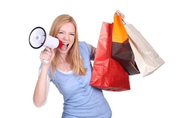 Woman holding shopping bags and screaming through a megaphone — Stock Photo, Image