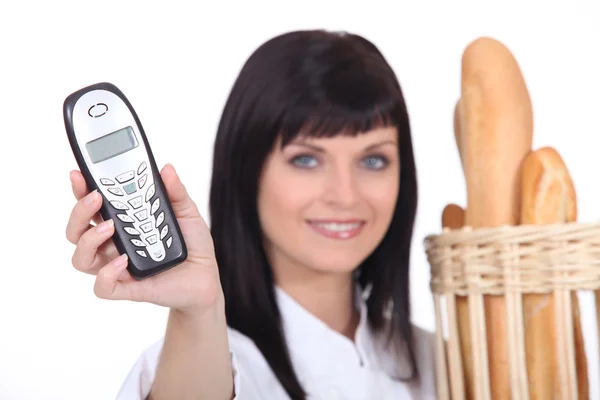 Femme tenant téléphone portable et pain — Photo
