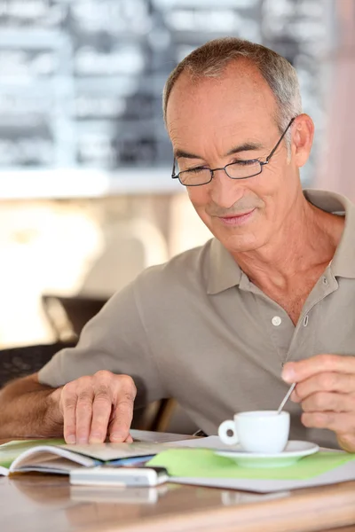 Old man drinking coffee and reading — Stock Photo, Image