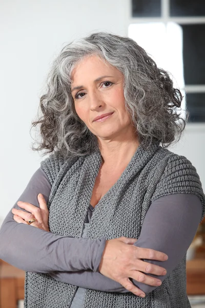 Donna dai capelli grigi in cucina con le braccia incrociate — Foto Stock