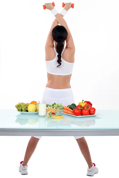 Mujer haciendo ejercicio de gimnasio frente a las verduras —  Fotos de Stock