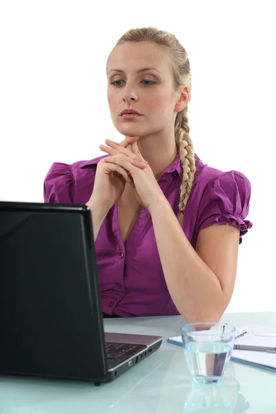 女人坐在桌前与玻璃水和便携式计算机的 — 图库照片