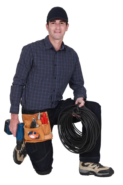 Eletricista ajoelhado com broca e cabo — Fotografia de Stock