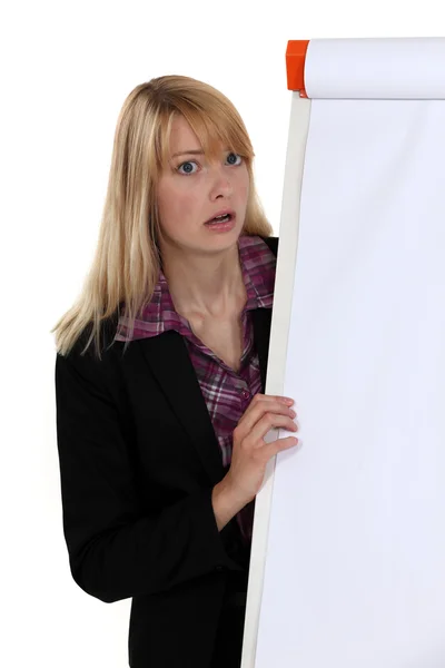 Wstrząśnięty blond kobieta stał przez pustą tablicę typu flip chart — Zdjęcie stockowe