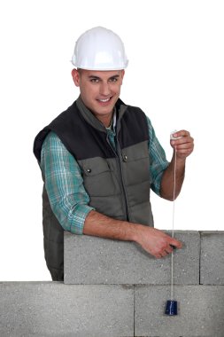 Tradesman holding a plumbline clipart