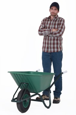 Tradesman standing behind a wheelbarrow clipart