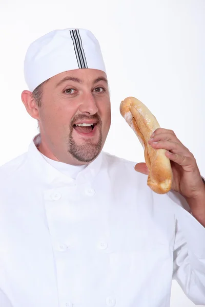 Podpuchnięte człowiek ubrany w piekarz jest jedzenie chleba — Zdjęcie stockowe