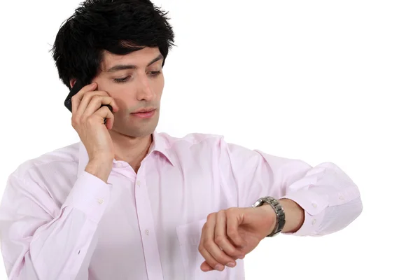 Homem falando em seu celular e observando seu relógio — Fotografia de Stock