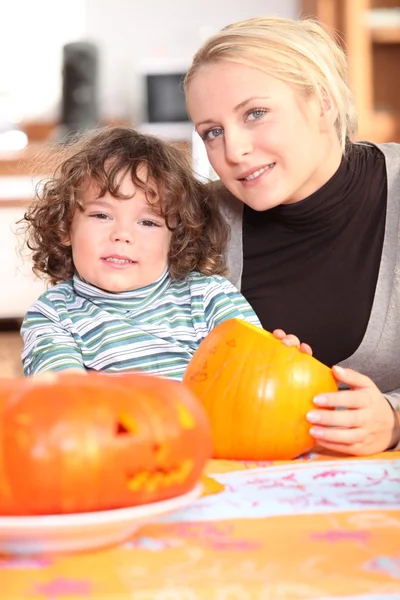 Žena řezbářské pumpkins se svým dítětem — Stock fotografie
