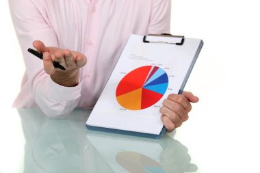 Businessman showing pie chart at meeting clipart