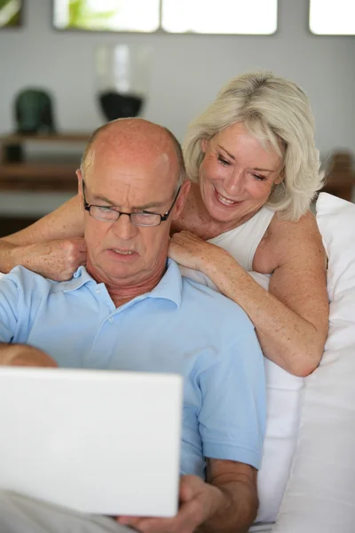 Senior couple sat on the sofa surfing the internet — Stock Photo, Image