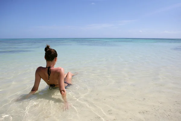 Morena sentada en una playa mirando hacia el horizonte — Foto de Stock