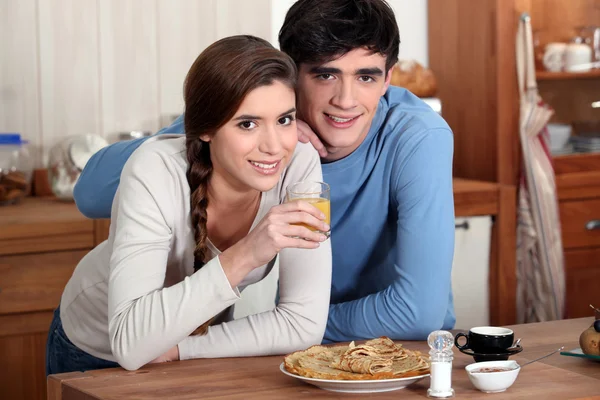 Ungt par i köket äta pannkakor — Stockfoto
