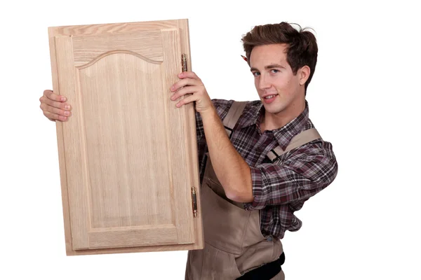 Um carpinteiro segurando uma porta do armário . — Fotografia de Stock
