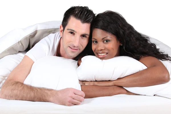 Homem e mulher sorrindo deitados em uma cama — Fotografia de Stock
