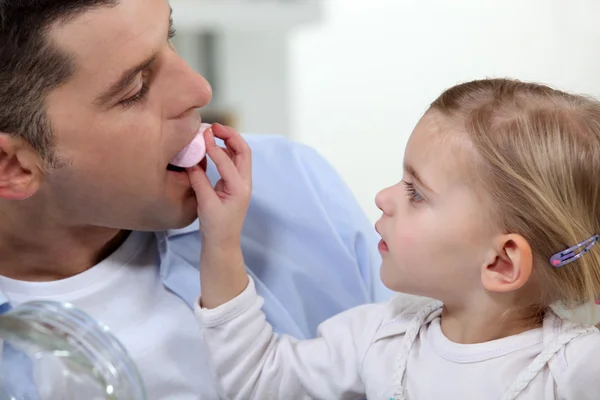 Отец и дочь едят зефир — стоковое фото
