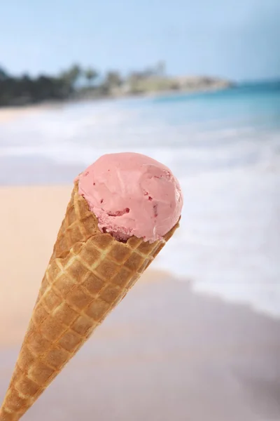 Jahodová zmrzlina kužel s pláží v pozadí — Stock fotografie