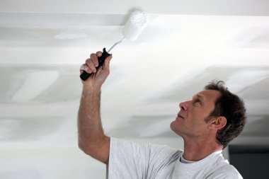 Man painting his ceiling white clipart